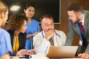 Group of people huddled behind a doctor's laptop