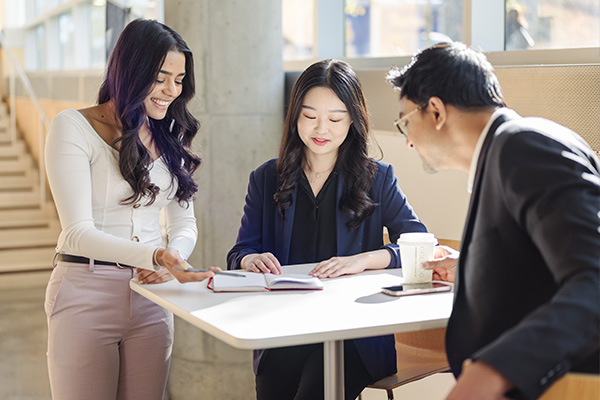 Three MSPM students talking at a table.