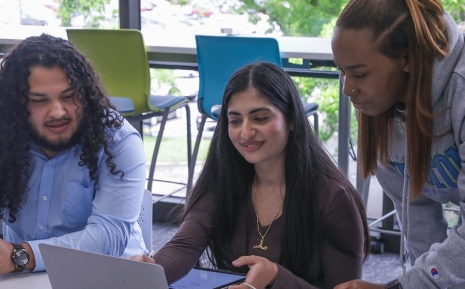 Three student around a laptop