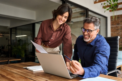 Man and woman using laptop at a meeting.
