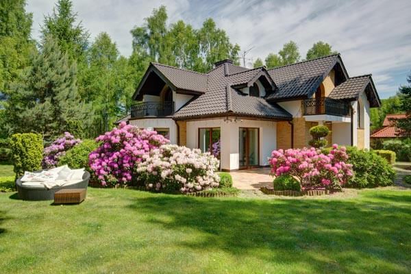 A charming home surrounded by a spacious lawn adorned with colorful flowers.