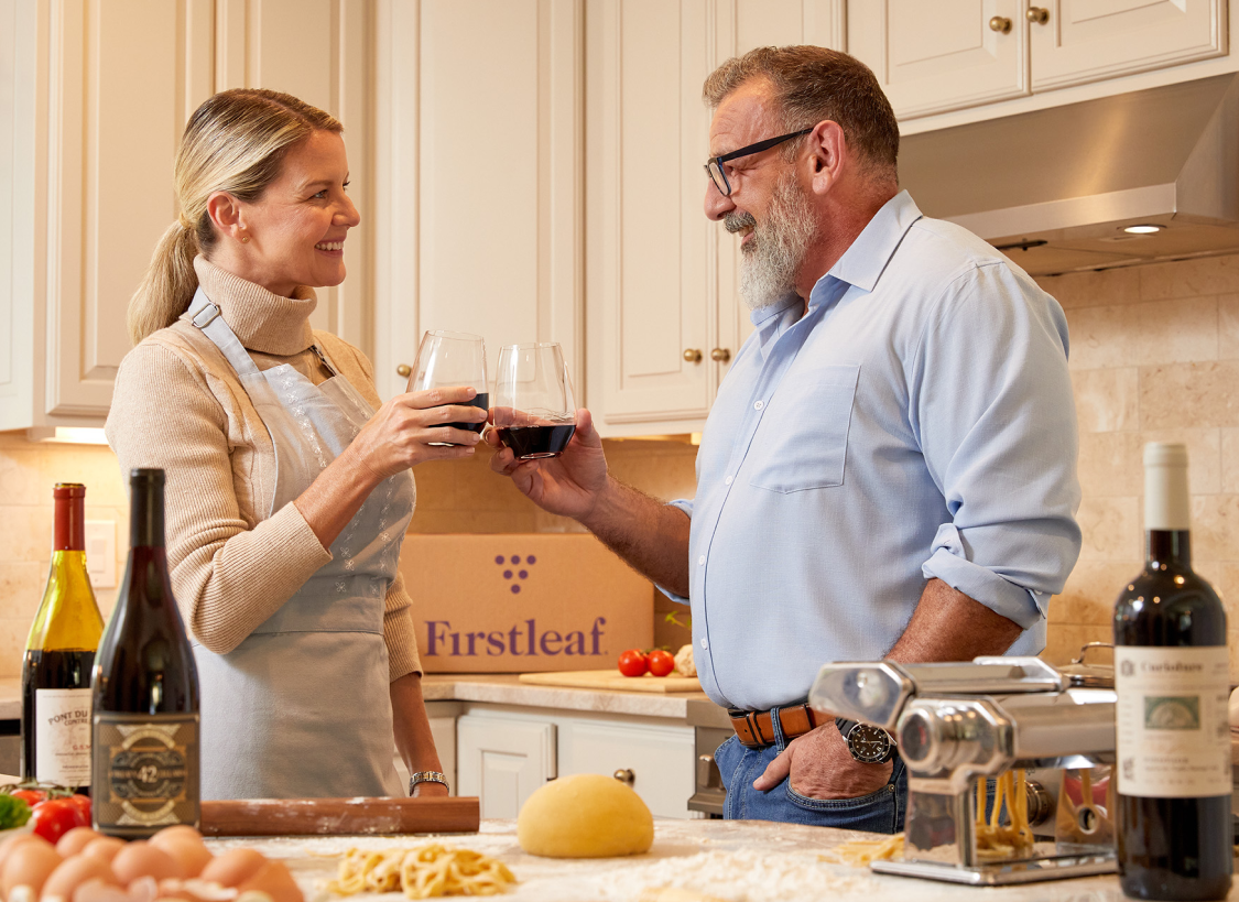 Couple in kitchen drinking firstleaf wine while making pasta