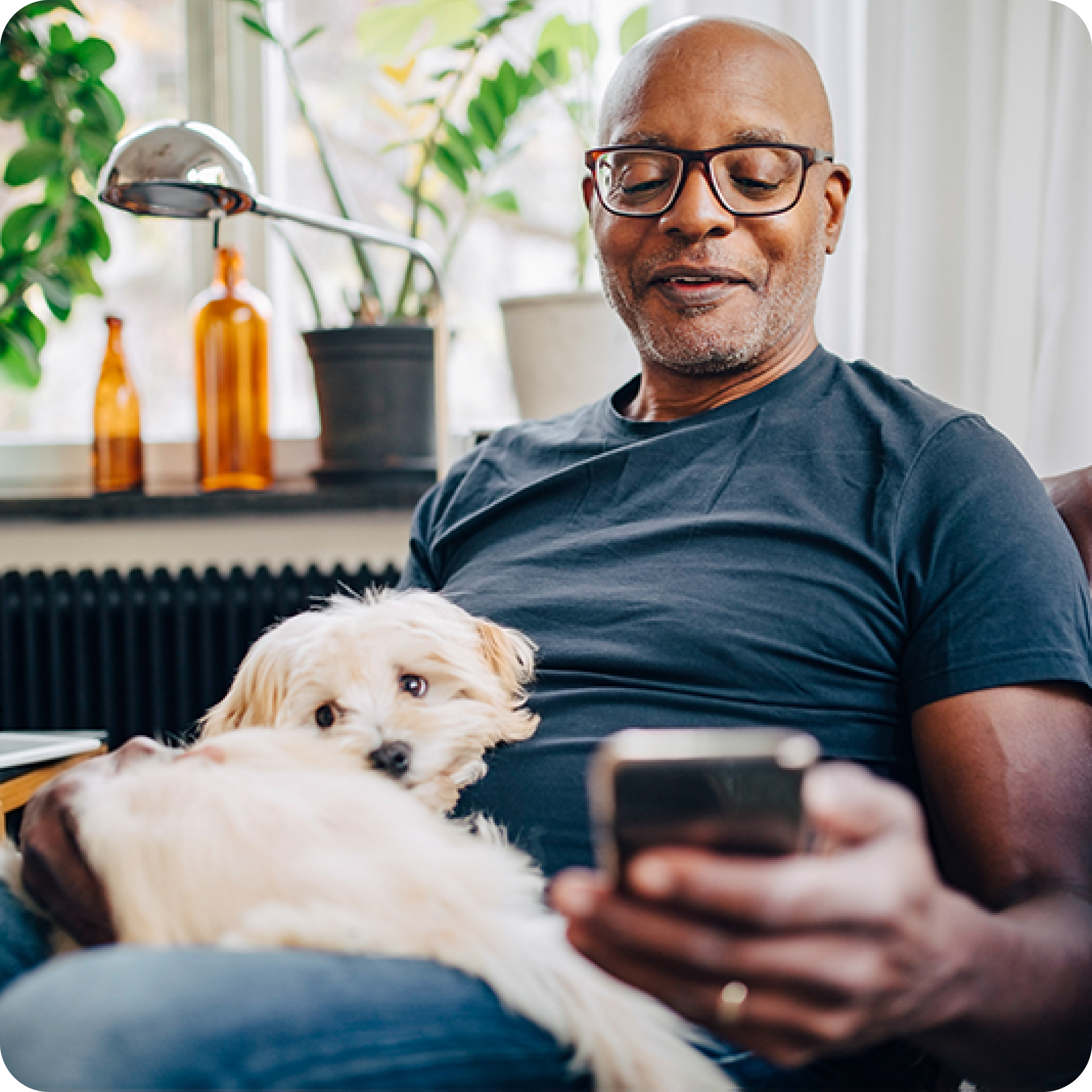 Man sitting on couch browsing on phone with Aura protection