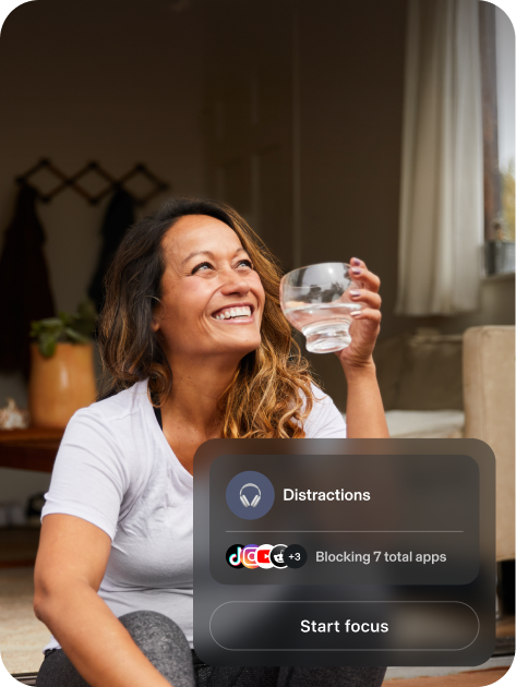 Woman smiling and drinking water. Bubble showing distractions blocking 7 applications.