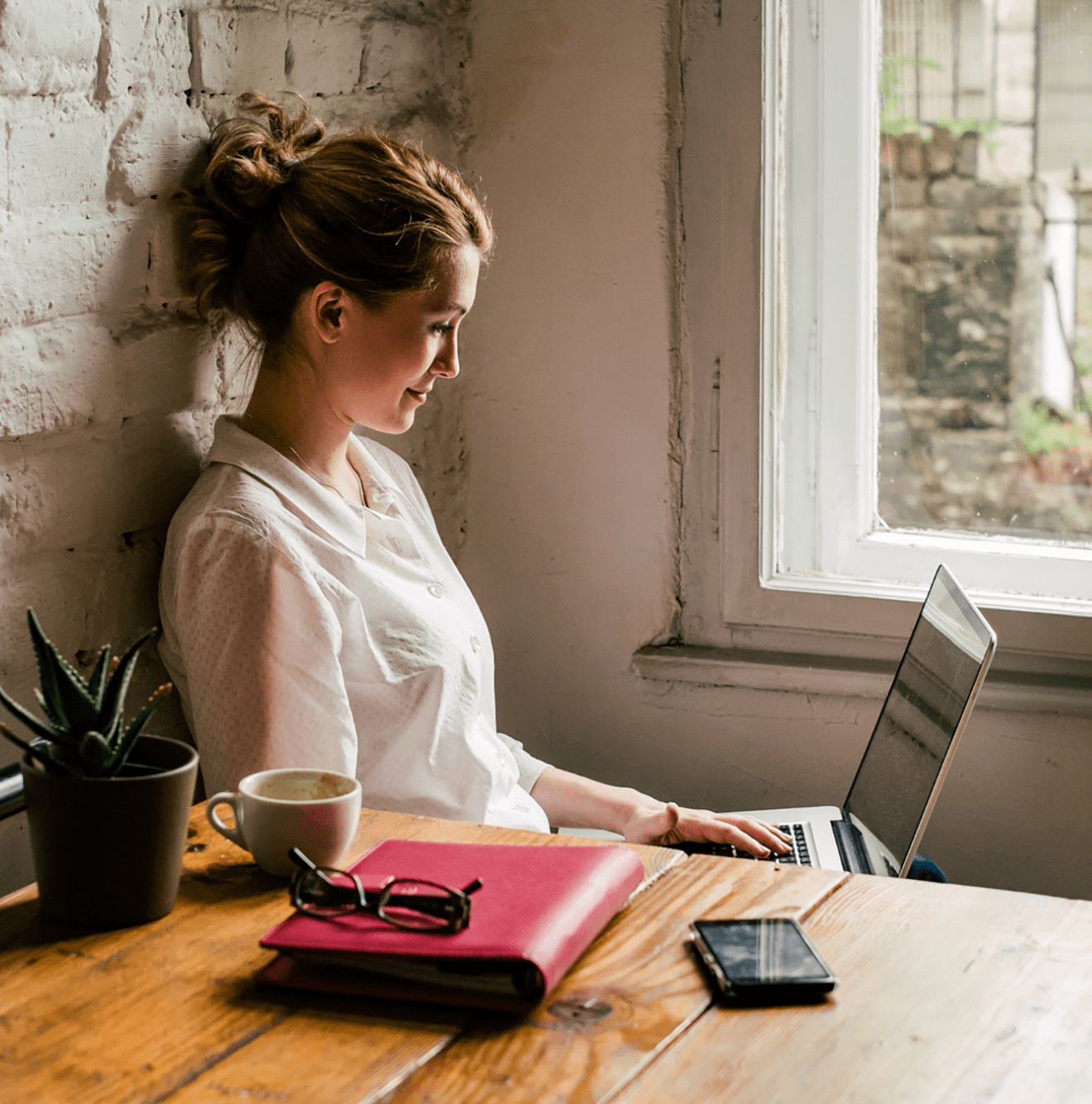 Woman leaning against wall viewing computer screen