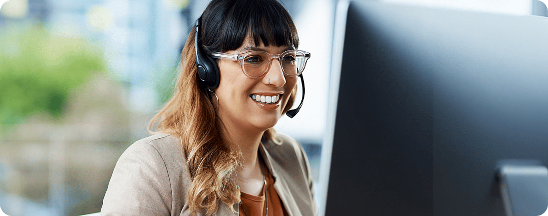 Customer Service Agent talks on her headset while looking at her screen
