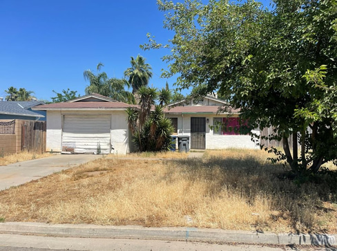 Older home with a detached carport and worn exterior, suitable for renovation or cash sale.