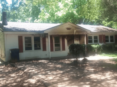 Older home with a detached carport and worn exterior, suitable for renovation or cash sale.