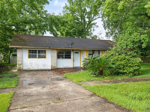 Older home with a detached carport and worn exterior, suitable for renovation or cash sale.