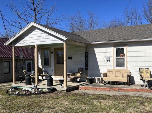 Older home with a detached carport and worn exterior, suitable for renovation or cash sale.