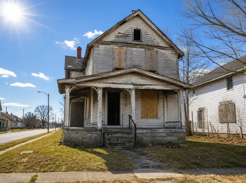 Older home with a detached carport and worn exterior, suitable for renovation or cash sale.