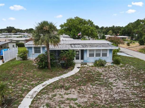 Older home with a detached carport and worn exterior, suitable for renovation or cash sale.