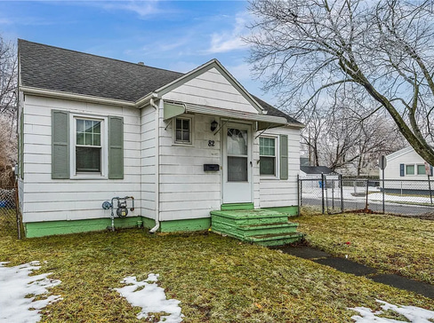Older home with a detached carport and worn exterior, suitable for renovation or cash sale.