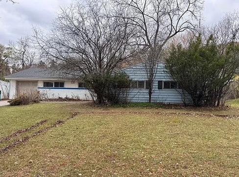 Older home with a detached carport and worn exterior, suitable for renovation or cash sale.