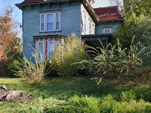 Older home with a detached carport and worn exterior, suitable for renovation or cash sale.