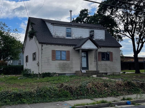 Single-story home with dated exterior and minimal landscaping, ideal for a fixer-upper sale.