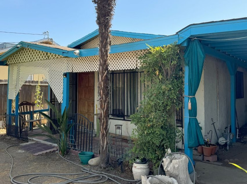 Older home with a detached carport and worn exterior, suitable for renovation or cash sale.