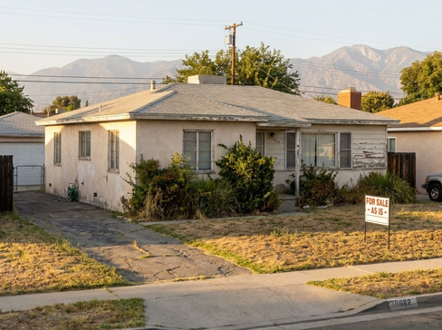 Older home with a detached carport and worn exterior, suitable for renovation or cash sale.
