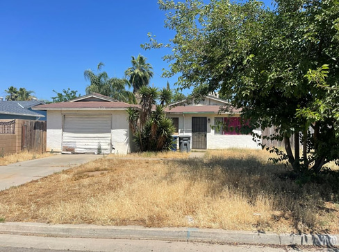Older home with a detached carport and worn exterior, suitable for renovation or cash sale.