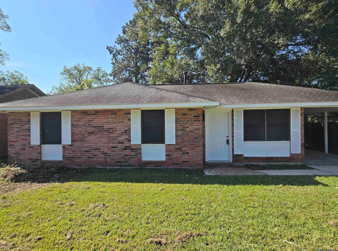 Single-story home with dated exterior and minimal landscaping, ideal for a fixer-upper sale.