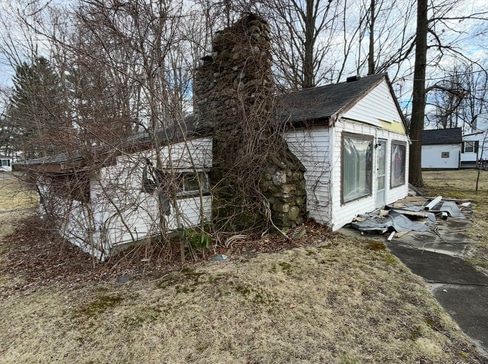 Older home with a detached carport and worn exterior, suitable for renovation or cash sale.