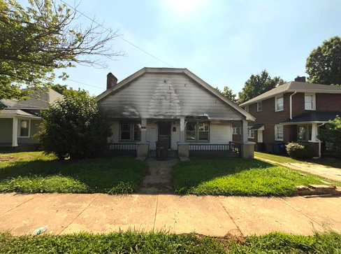 Older home with a detached carport and worn exterior, suitable for renovation or cash sale.