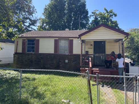 Older home with a detached carport and worn exterior, suitable for renovation or cash sale.