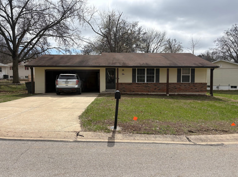 Single-story home with dated exterior and minimal landscaping, ideal for a fixer-upper sale.