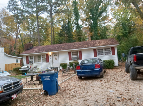Older home with a detached carport and worn exterior, suitable for renovation or cash sale.