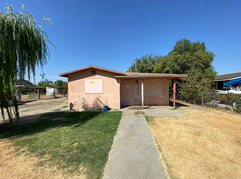 Older home with a detached carport and worn exterior, suitable for renovation or cash sale.