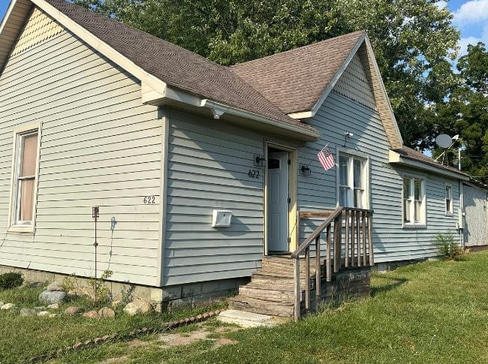 Single-story home with dated exterior and minimal landscaping, ideal for a fixer-upper sale.