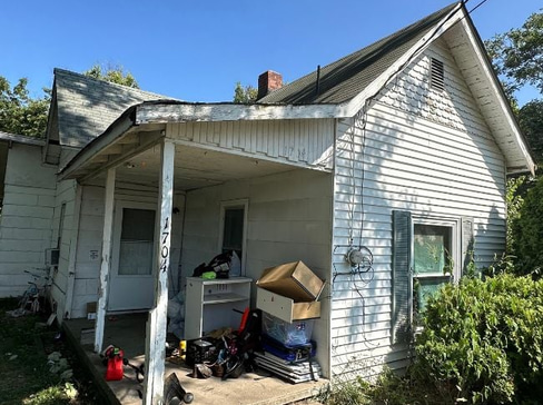 Older home with a detached carport and worn exterior, suitable for renovation or cash sale.