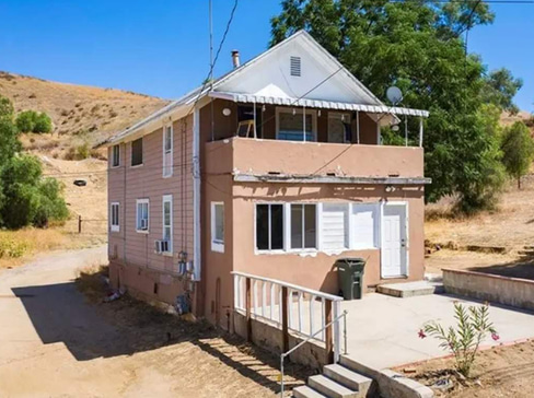 Older home with a detached carport and worn exterior, suitable for renovation or cash sale.