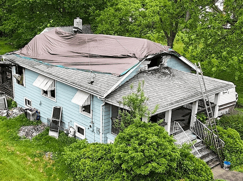 Older home with a detached carport and worn exterior, suitable for renovation or cash sale.