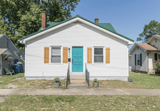 Older home with a detached carport and worn exterior, suitable for renovation or cash sale.