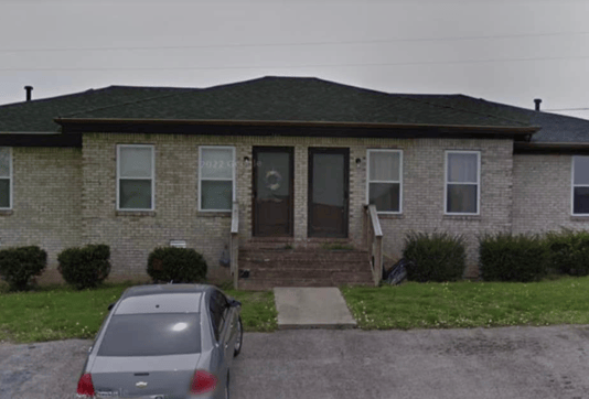 Older home with a detached carport and worn exterior, suitable for renovation or cash sale.