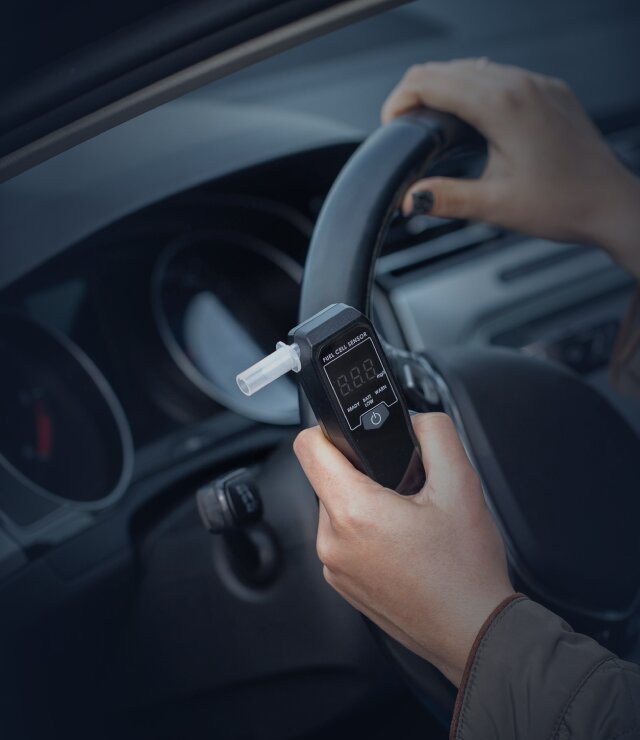 Driver at the wheel holding a breathalyzer