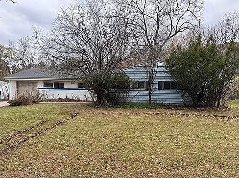 Older home with a detached carport and worn exterior, suitable for renovation or cash sale.