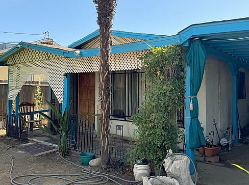 Older home with a detached carport and worn exterior, suitable for renovation or cash sale.