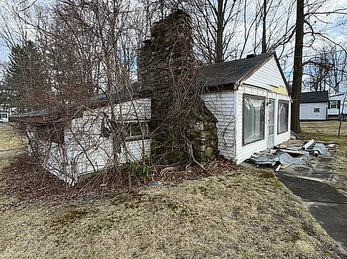 Older single-story home with worn exterior, suitable for renovation or cash purchase.