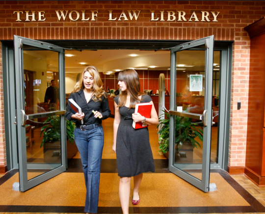 two women holding books outside the Wolf Law Library
