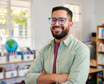 A smiling student in a red sweater studies in a library
