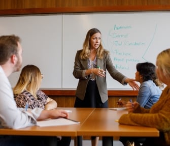 A female KU business professional teaching future financial analysts.