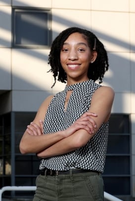 A female CSUSB business student smiling with crossed arms.