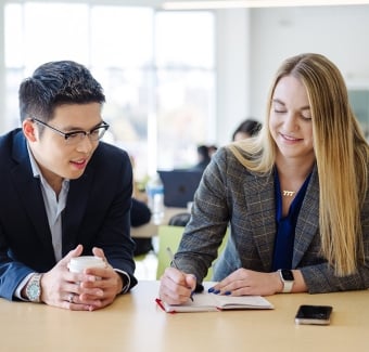Two students talking and taking notes