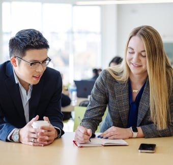 Two students talking and taking notes