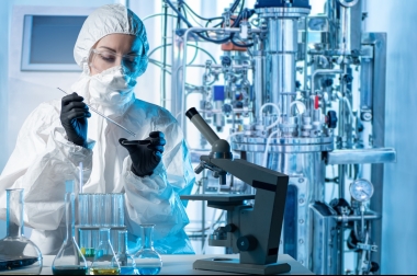 A female lab tech reviews a culture sample with microscope.