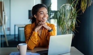 Young female smiles while sitting in front of laptop.