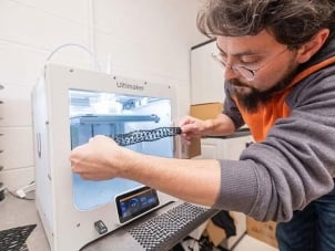 A male student works with a 3D printer.