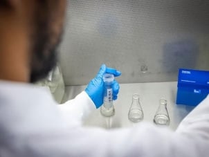 A biomedical student measuring liquid into a test tube.